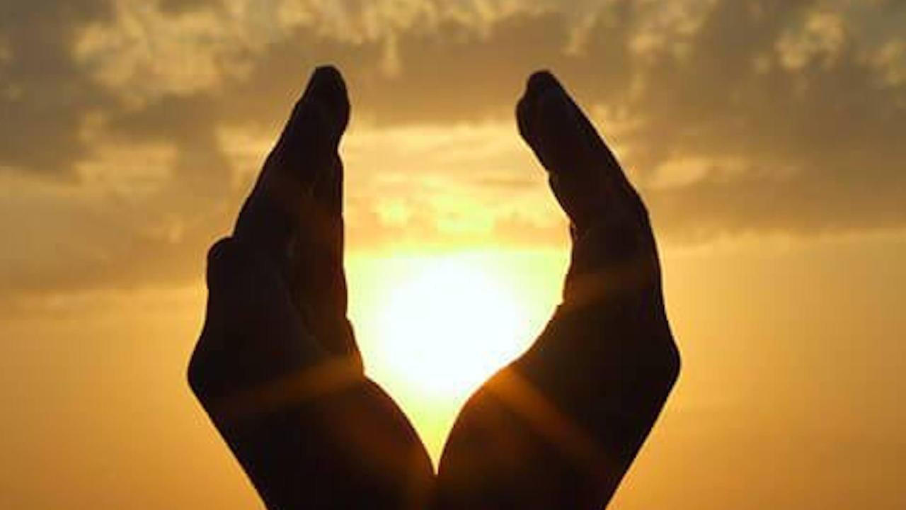 The outline of two hands cupping the sun for The DEN's Reiki 1 & 2 Certifications with Jamie Wozny