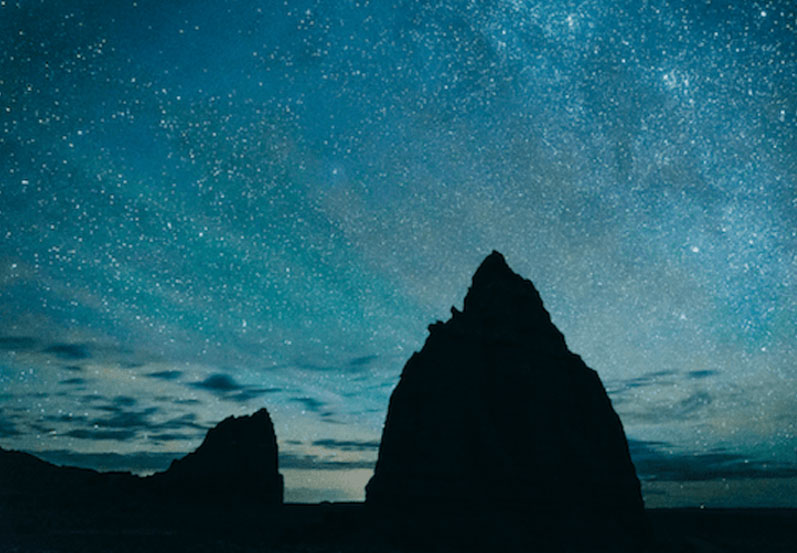 Silhouette of a rocky outcropping on a twilight beach signfies the future of online meditation classes with The DEN Meditation